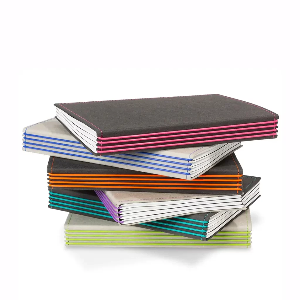 Stapel modularer X17-Planer in grauem und schwarzem veganen Texon mit markanten, farbigen Gummibändern am Buchrücken.