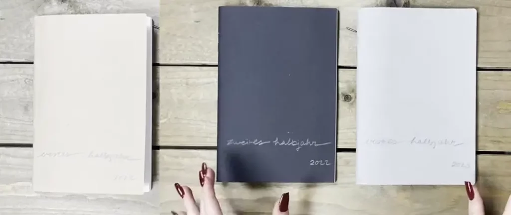 X17 Bullet Journal mit modularen Heften in verschiedenen Farben, handschriftlich beschriftet nach Halbjahren auf hellem Holz.