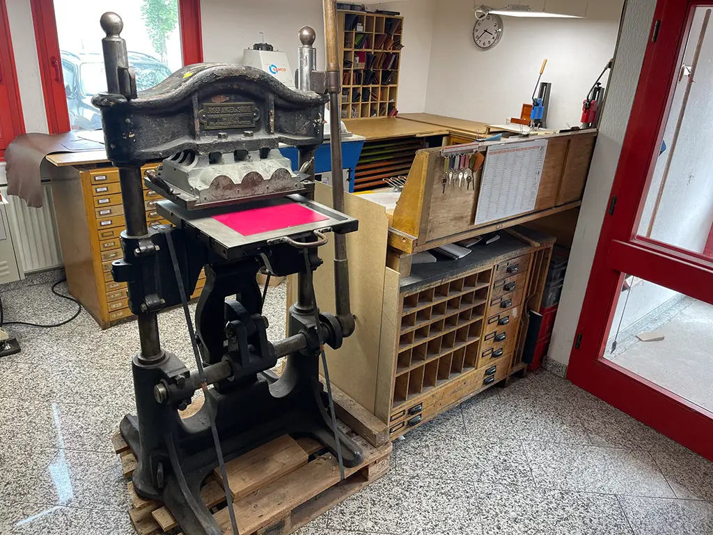 Eine historische gusseiserne Handstanze der Firma Josef Anger & Söhne in einer Lederwerkstatt, die die lange Geschichte des traditionellen Handwerks verkörpert