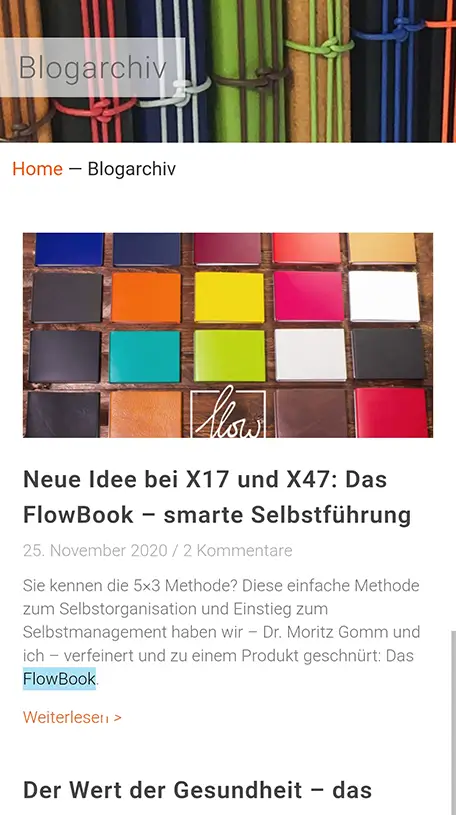 Screenshot einer mobilen Blog-Archivseite. Oben ein Banner mit farbigen, gebündelten Stiften und dem Titel „Blogarchiv“. Darunter ein Blogbeitrag mit einem Foto von bunten quadratischen Karten auf einem Holztisch. Die Überschrift lautet „Neue Idee bei X17 und X47: Das FlowBook – smarte Selbstführung“. Unter der Überschrift stehen das Datum „25. November 2020“, die Angabe „2 Kommentare“, ein kurzer Beschreibungstext sowie der Link „Weiterlesen >“